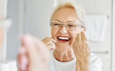 Woman smiling while flossing her teeth