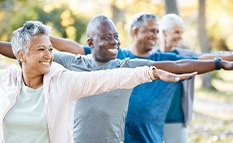 Group of adults smiling while stretching in park