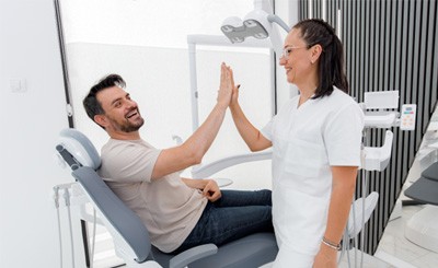 Happy patient high-fiving dental team member