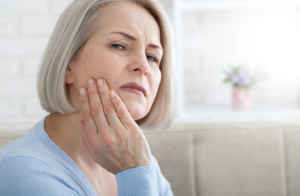 Woman with dry socket touching jaw and looking concerned