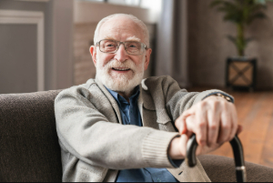 Bearded senior man with cane sitting in chair and smiling