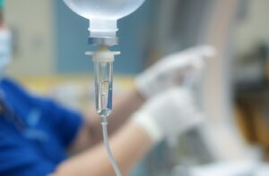 IV shown in foreground while dental staff member works in background.